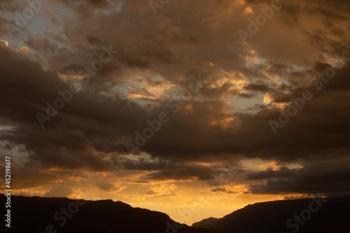 	
Cloudscape. Magical view of a dramatic sunset in the mountains. The beautiful sky, clouds and mountain dark silhouette with dusk colors.