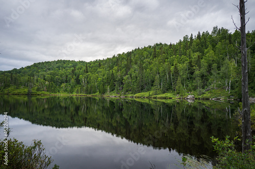 Reflections on a cloudy day in the waters of the small Lac des Pères at the beginning of Pic de la Tête de Chien hiking trail in Monts Valin National Park in Quebec (Canada)
