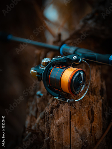 Fishing reel, blurred background. Fisherman with rod, spinning reel on the river bank photo