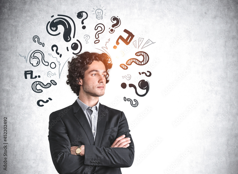 Serious businessman is standing near sketch with question marks Serious businessman is standing near sketch with question marks