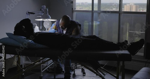 Tattoo artist working with client