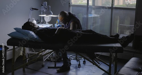 Tattoo artist working with client