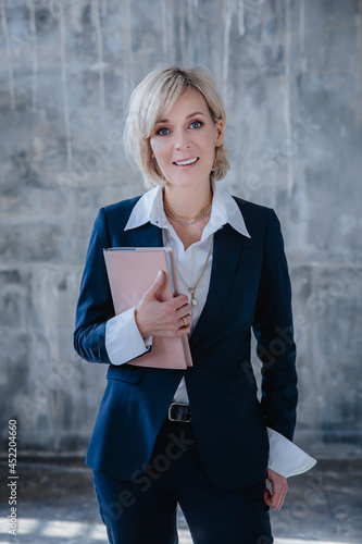 A beautiful business woman in a business suit poses with a notebook in her hands