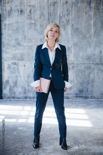 A beautiful business woman in a business suit poses with a notebook in her hands
