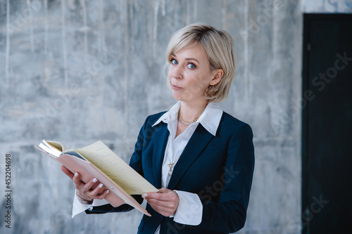 A beautiful business woman in a business suit poses with a notebook in her hands