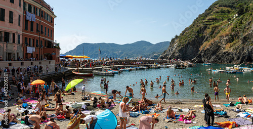 people swim and sunbathe in the sea of the small village of Vernazza, Cinque Terre, La Spezia, Italy