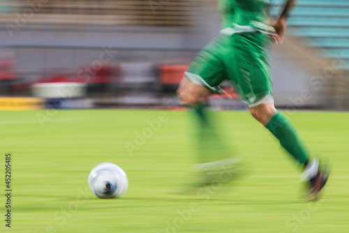 Football player runs with ball during match - blurred motion due to long exposure © Dziurek