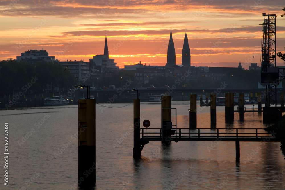 Beautiful sunrise with dramatic sky at the River Weser in Bremen, Germany with church towers at the city scape