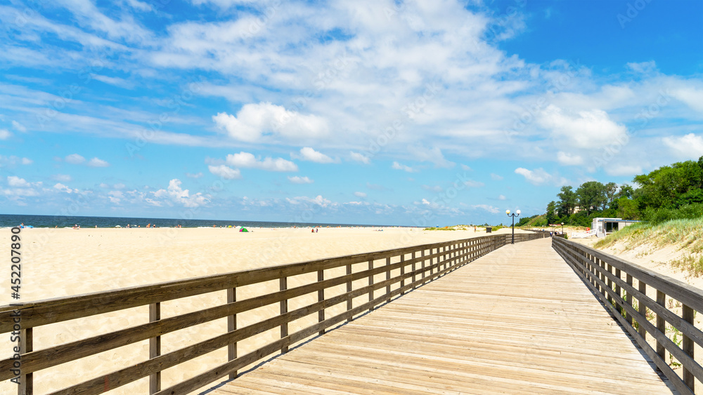 Long wooden promenade along the sandy beach of the Baltic Sea in the village of Yantarny, Kaliningrad region, Russia