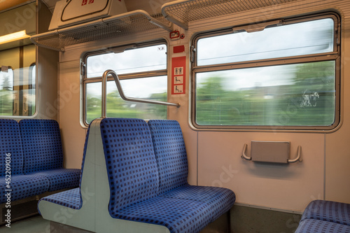 Interior view of a corridor inside passenger trains with blue fabric seats of German railway train system. Empty vacant passenger car inside the Tram.
