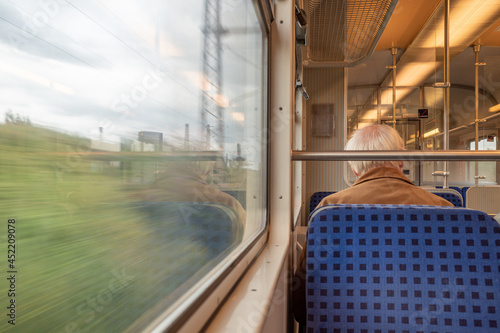 Fotografija Interior and selected focus view at the back of elder male passenger with face protection mask and skinhead who sit in tram or train in Germany