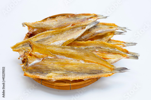 Sun dried black kingfish in bamboo basket on white background.