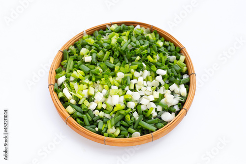 Chopped spring onions in bamboo basket on white background.