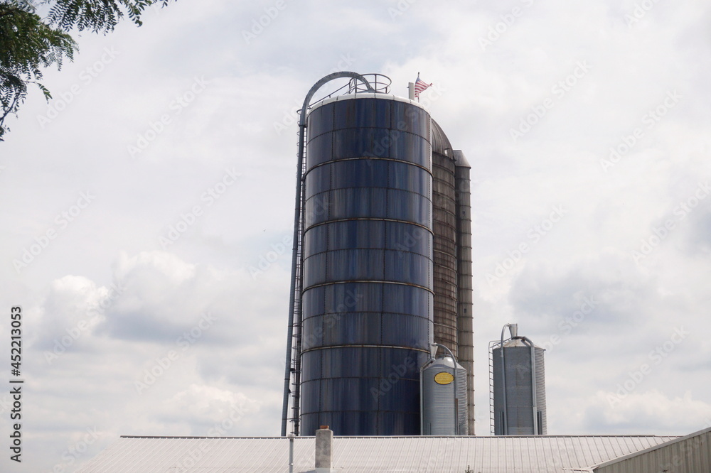 Blue and Weathered Silos With American Flag Against Sunny Summer Sky
