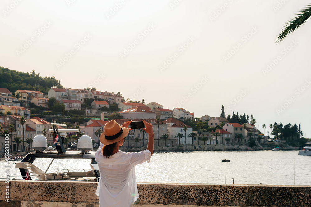 Girl tourist photographs the sea bay and buildings in Korcula town, Croatia