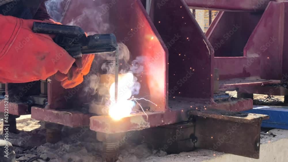 Construction worker welds two metal parts together at construction site. Semi-automatic arc welding. Close-up of welding works. Construction worker welds two metal parts together at construction site. Semi-automatic arc welding. Close-up of welding works.