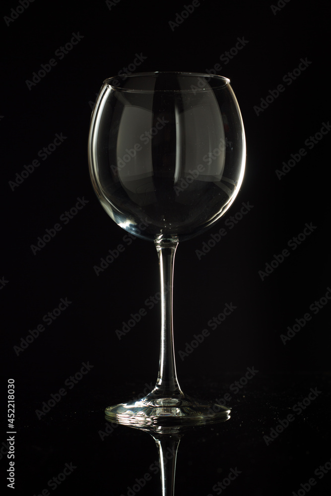 A studio shot of an elegant, isolated wine glass on black with reflections