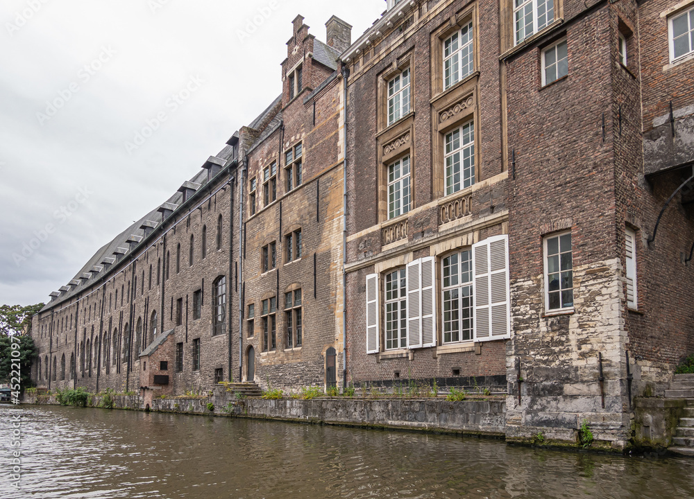 Gent, Flanders, Belgium - July 30, 2021: Brown brick back facade along Leie River of former medieval  Dominican Cloister, now University center. Famous during Protestant revolution in 16th century.