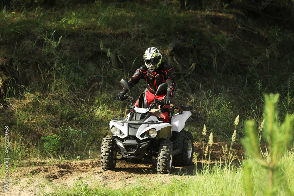 Man driving modern quad bike on sandy road near forest. Extreme sport Man driving modern quad bike on sandy road near forest. Extreme sport