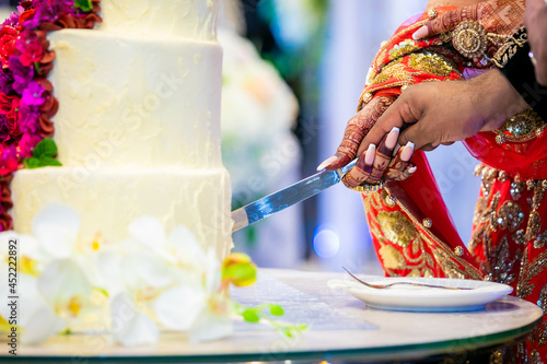 Indian couple's hands cutting wedding cake, hands and knife close up