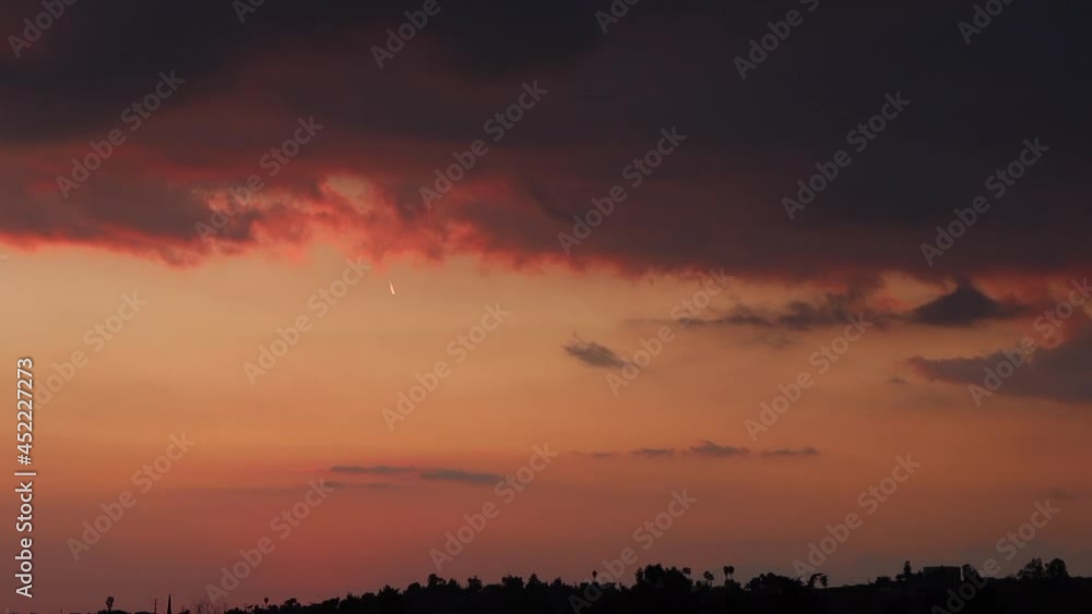 A Dramatic Cloudy Sunset in a California Sky with Palm Trees Silhouettes A Dramatic Cloudy Sunset in a California Sky with Palm Trees Silhouettes