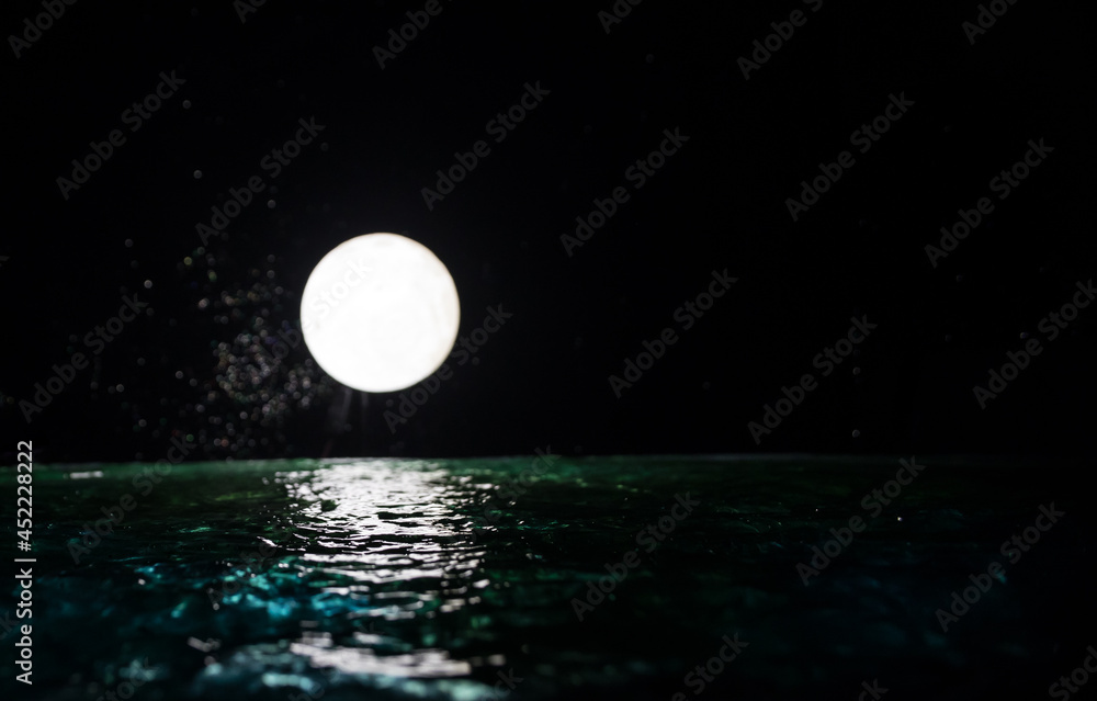Fototapeta premium Romantic and scenic panorama with full moon on sea to night. Table decoration with moon miniature and water.