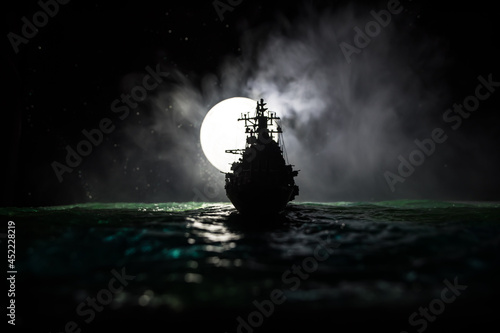 Silhouettes of a crowd standing at blurred military war ship on foggy background Fotobehang