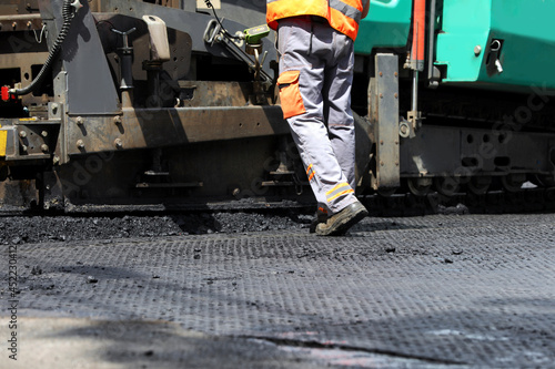 Worker laying new asphalt with paver, closeup. Road repair