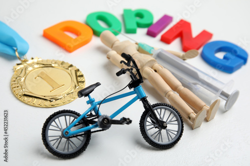 Word Doping, syringe, medal, sportsman and bicycle model on white table photo