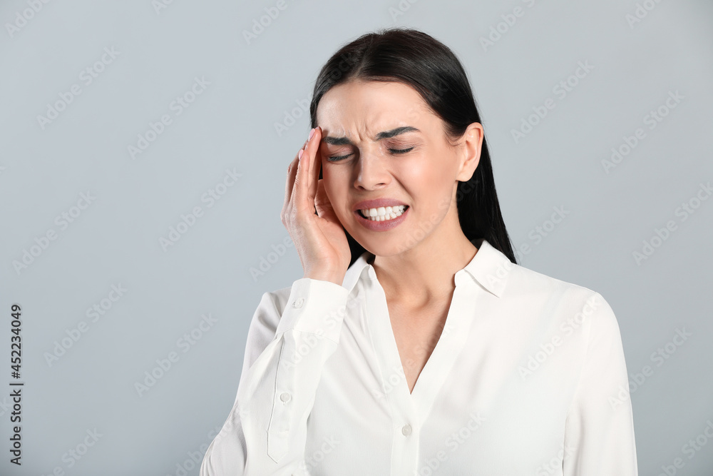 Woman suffering from migraine on grey background Woman suffering from migraine on grey background