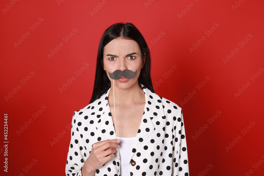 Emotional woman with fake mustache on red background Emotional woman with fake mustache on red background