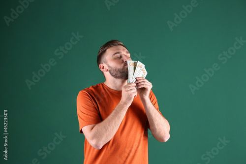 Greedy young man sniffing money on green background photo