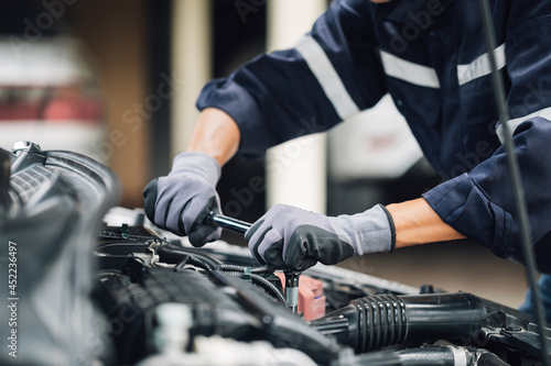 Mechanic works on the engine of the car in the garage. Repair service. Concept of car inspection service and car repair service.