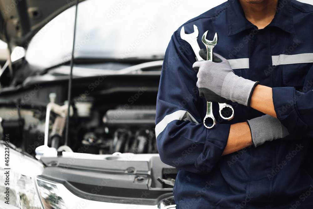 Hand of car mechanic with wrench. Auto repair garage. mechanic works on the engine of the car in the garage. Repair service. Concept of car inspection service and car repair service. - obrazy, fototapety, plakaty 