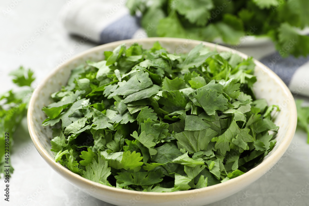 Cut fresh green cilantro in bowl on light grey table, closeup Cut fresh green cilantro in bowl on light grey table, closeup