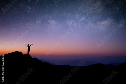 Silhouette of young female traveler and backpacker watched the star and milky way alone on top of the mountain before sunrise. She enjoyed traveling and was successful when he reached the summit.