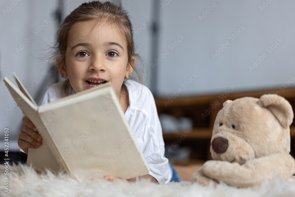 Little girl reads a book with a teddy bear. Little girl reads a book with a teddy bear.
