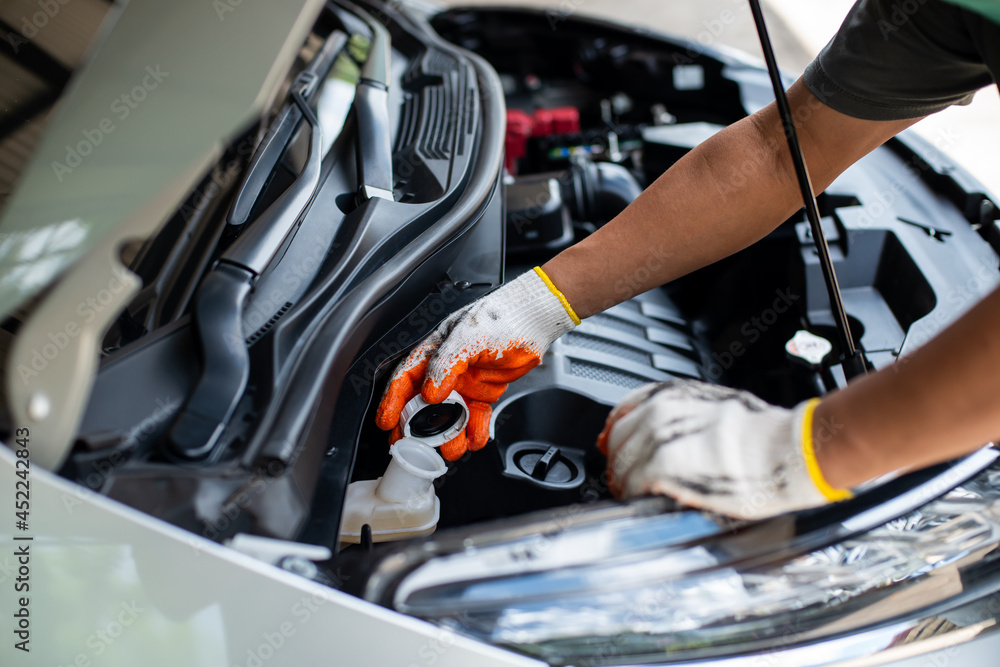 The mechanic's hands are checking the oil level. The mechanic's hands are checking the oil level.