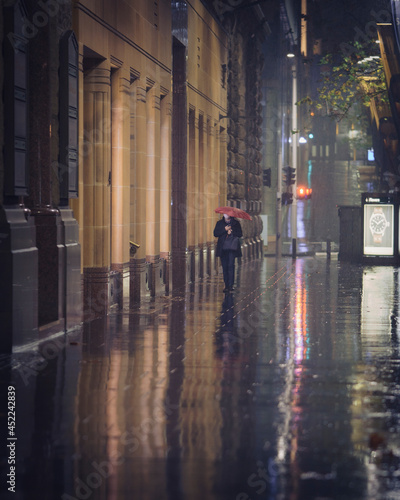 Lonely person walking in the city in the rain with an umbrella