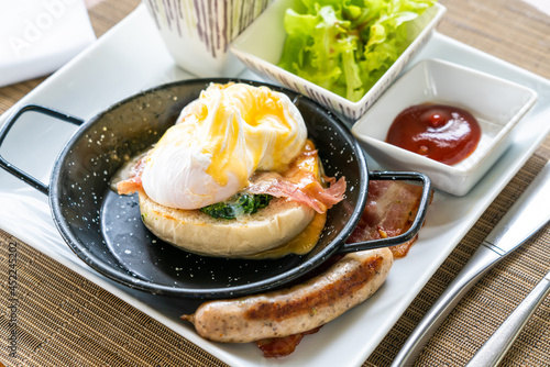 Egg benedict with bacon and sausage - delicious american breakfast