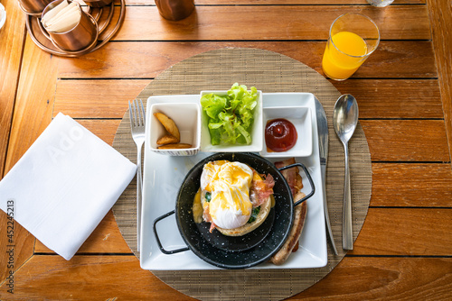 Egg benedict with bacon and sausage - delicious american breakfast