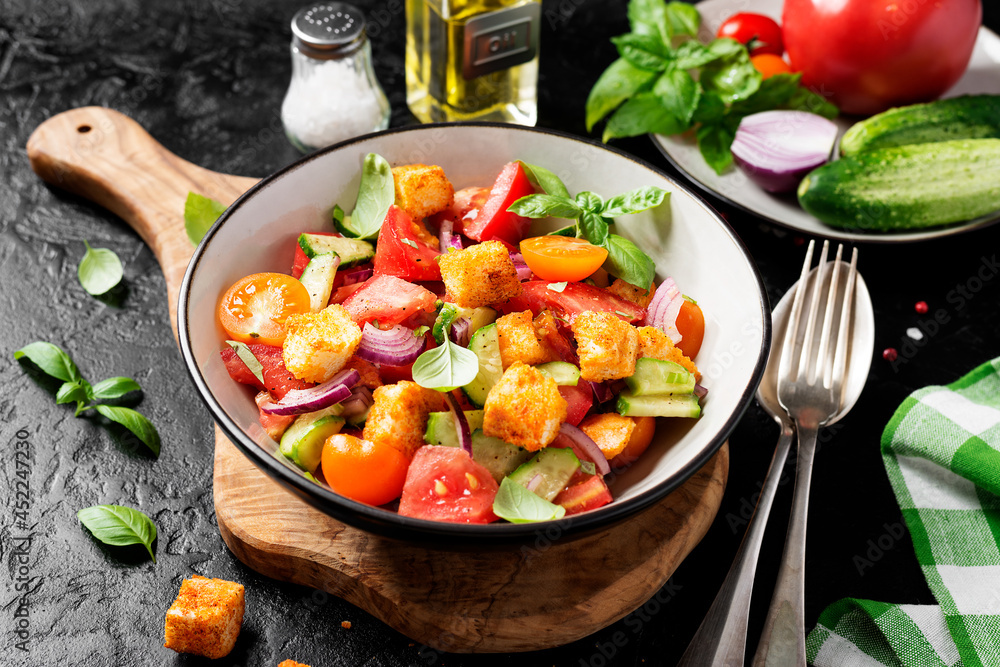 Tuscan Panzanella, traditional Italian salad with tomatoes and toasted bread. Vegetarian panzanella salad. Black background. Tuscan Panzanella, traditional Italian salad with tomatoes and toasted bread. Vegetarian panzanella salad. Black background.