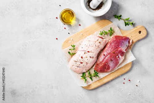 Preparation for cooking raw duck breast with ingredients. Light gray background, top view. Space for text photo