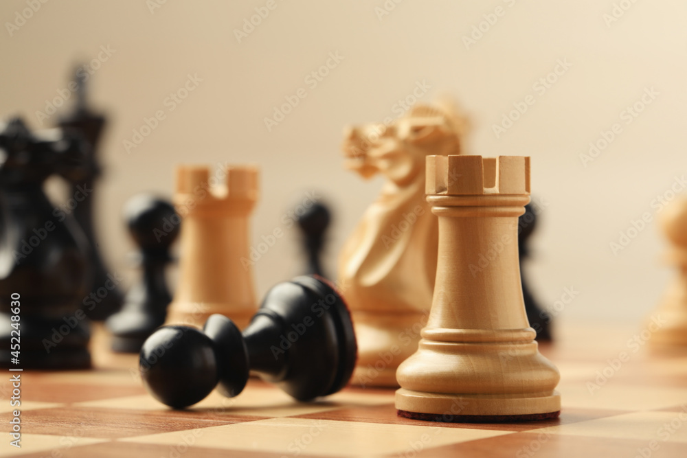 Chessboard with game pieces on beige background, closeup Chessboard with game pieces on beige background, closeup