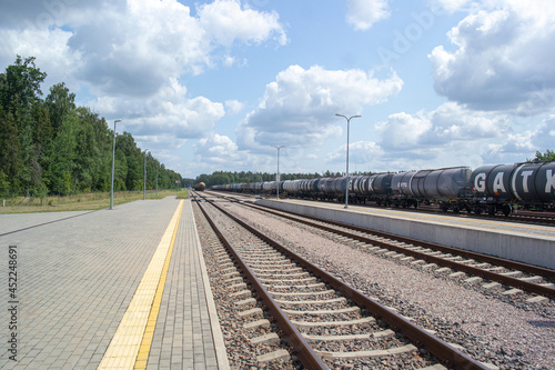 Railway station. Industrial landscape with the railroad, colourful blue sky, sun, trees and green grass. © vytautas