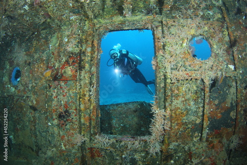 A female scuba diver exploring the inside of the Glen Nusa II shipwreck. Gili Island, Lombok, Indonesia.