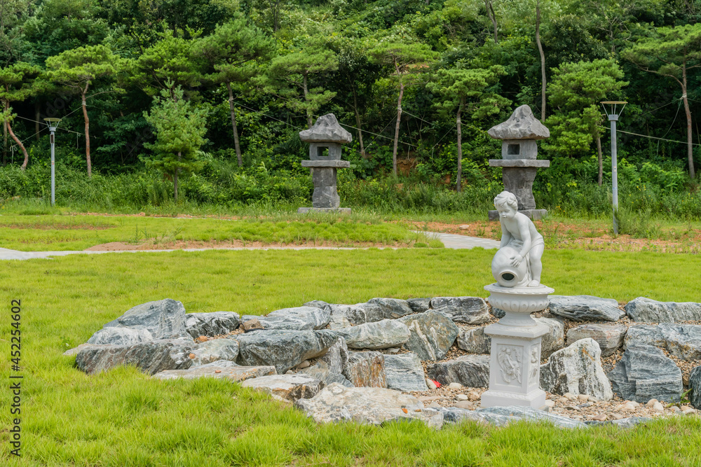 Dry stone circled water fountain with two large stone carved lanterns in background.
