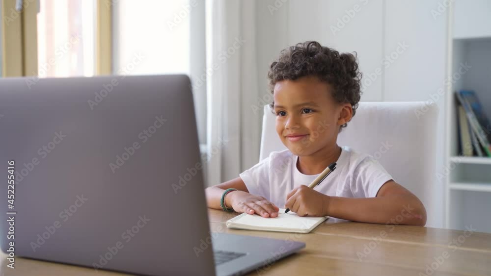 Cute little african american boy having online class using laptop doing homework Cute little african american boy having online class using laptop doing homework