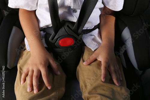Little boy fastened with car safety belt in child seat, closeup © New Africa