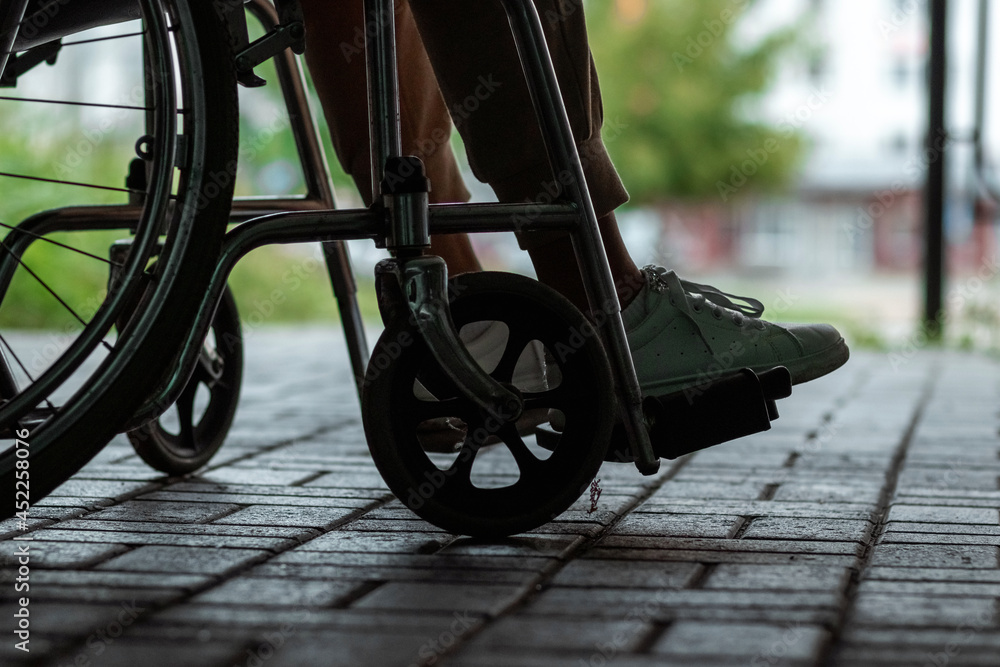Close-up of a leg on a wheelchair in the street. Disease recognition, disability, serious condition.